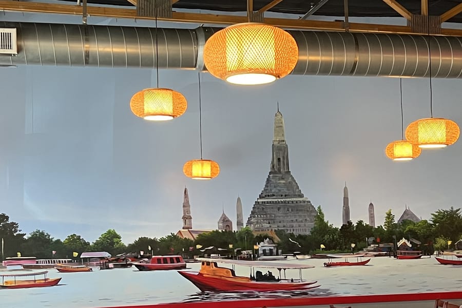 The dining room, with rattan pendant lights over a painted mural of the Chao Phraya river